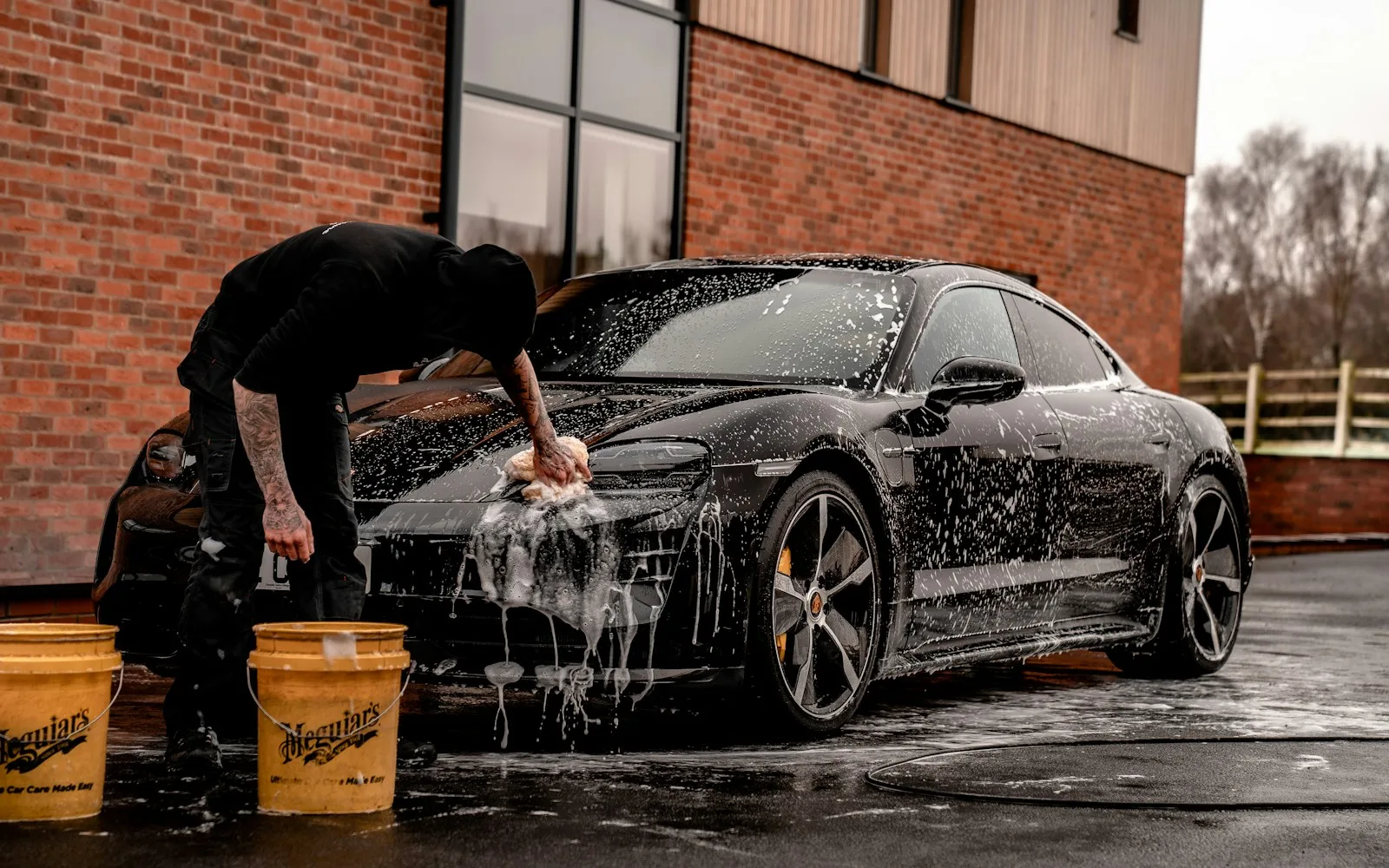 A premium black car being hand detailed in a modern studio